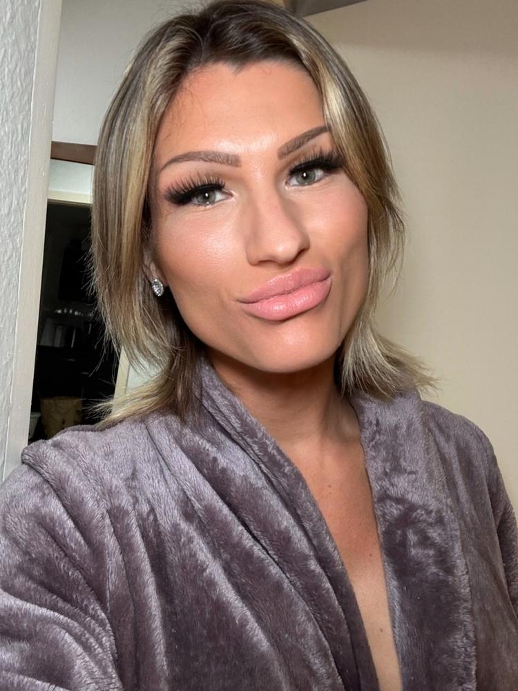 Kim Wagner in einem Selfie mit blondem Haar, sinnlichem Make-up und verführerischem Blick im samtigen Bademantel.