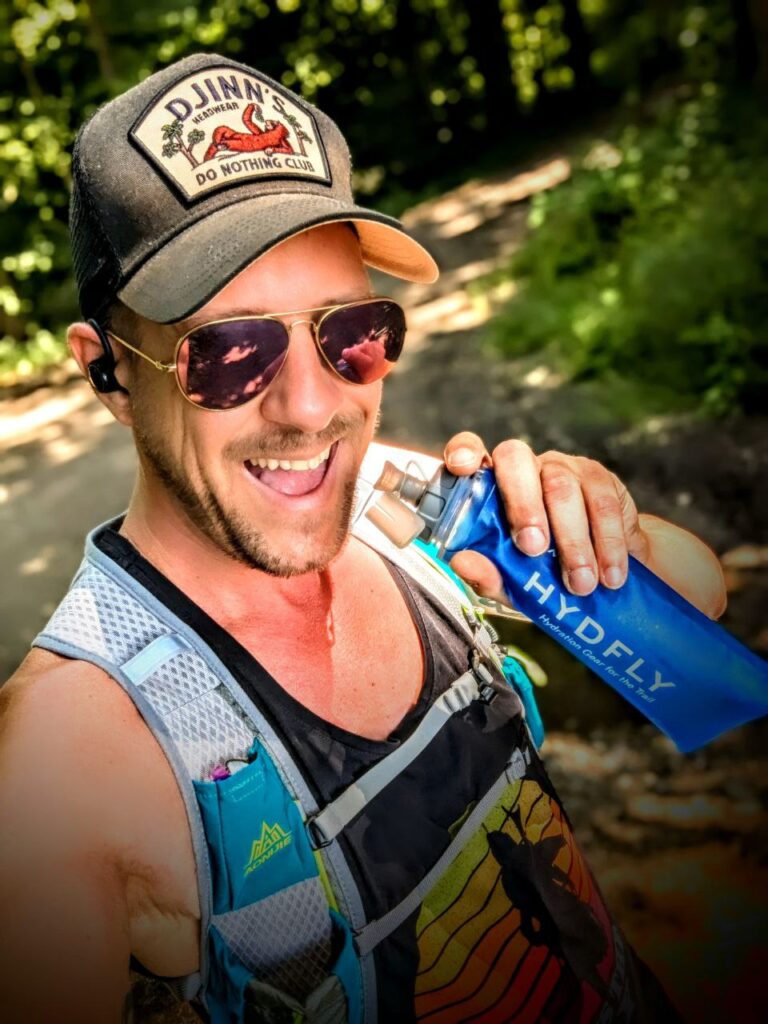 BDSM KINKY Larry Ragnarök Adler trinkt motiviert beim Joggen aus seiner Wasserflasche – ein aktiver Sexperte in Bewegung.